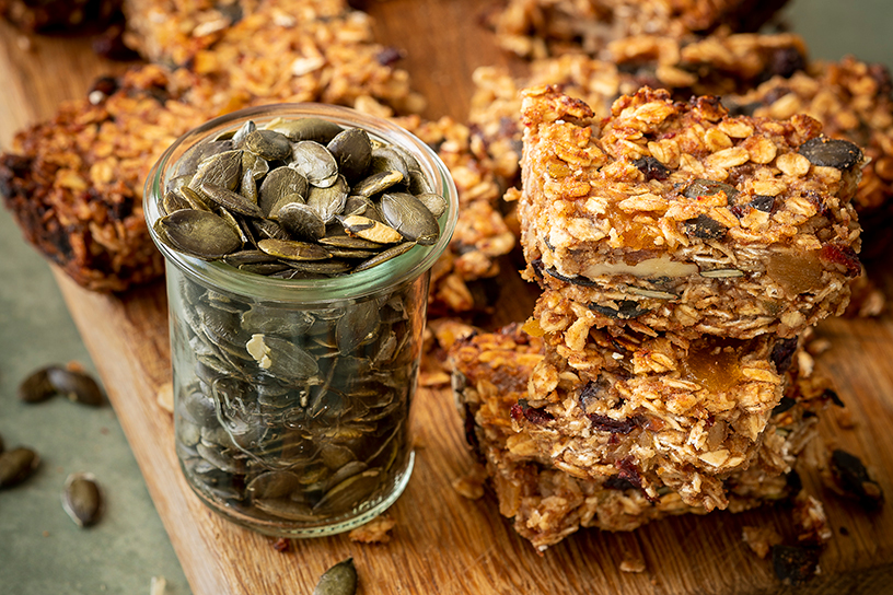 potje met pompoenpitten en havermoutrepen op plank