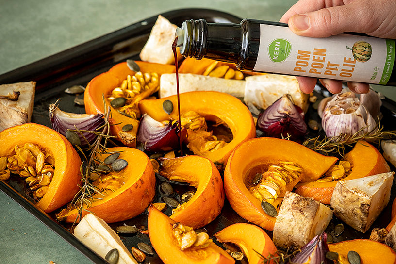 geroosterde groentes met pompoenpitolie op bakplaat.