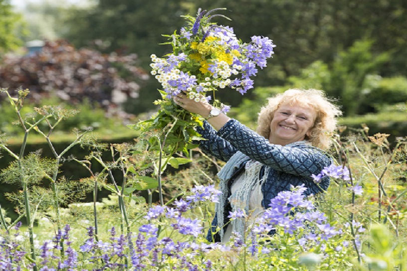 Mevrouw met een bos geplukte bloemen in de tuin