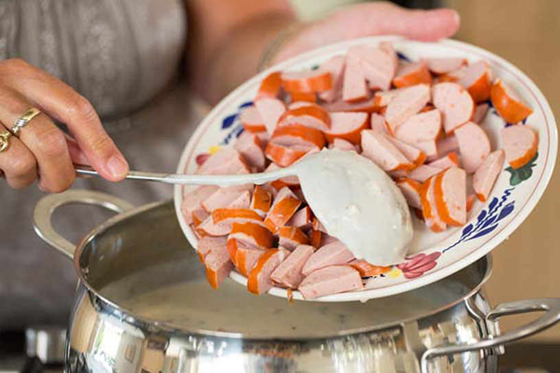 Rookworst overscheppen in een pan melkmoes soep