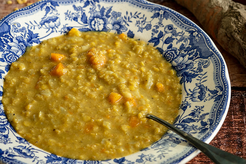 Gele linzensoep met winterwortel op bord.