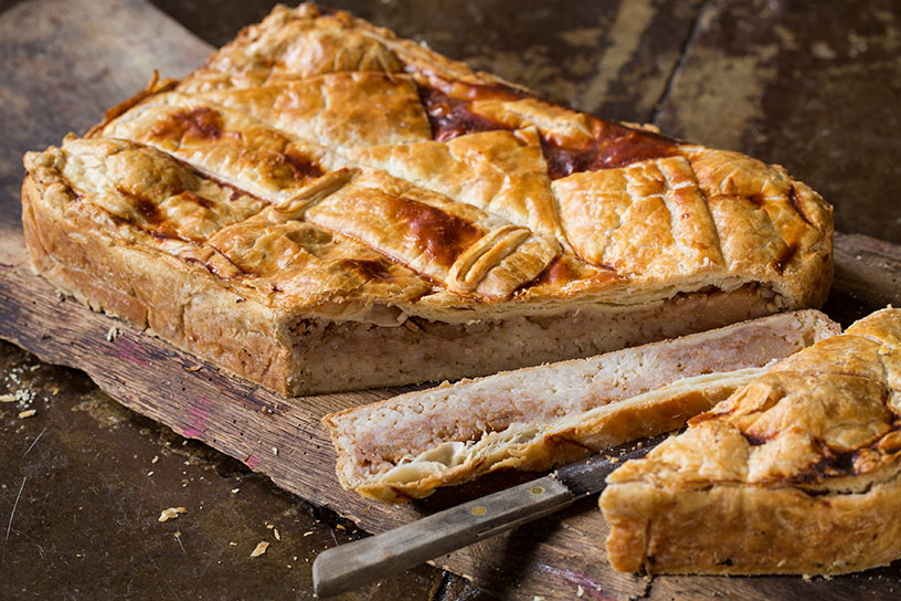 Driekoningentaart in stukken gesneden op een houten plank